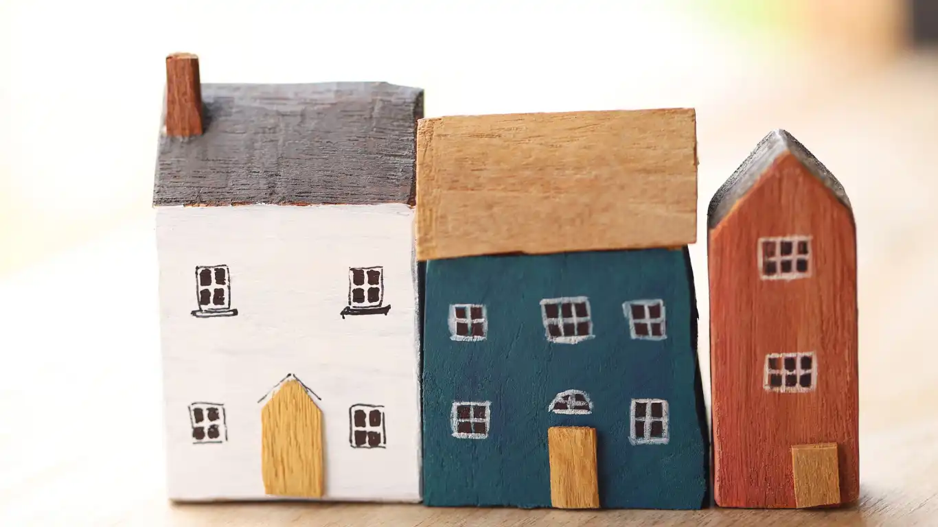 Maquetas de viviendas representando la necesidad de ajustar la descripción registral y catastral en procesos de compraventa e hipoteca